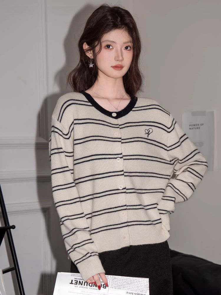 Woman wearing a cream and black striped button-up knit cardigan with a V-neck and embroidered detail.
