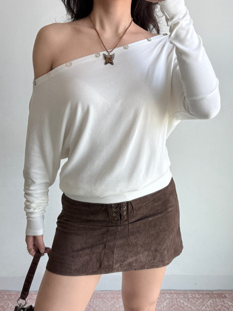 Woman adjusting her white off-the-shoulder knit top.