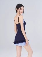 Back view of the model wearing the navy blue one-piece swimsuit with light blue gingham hem.
