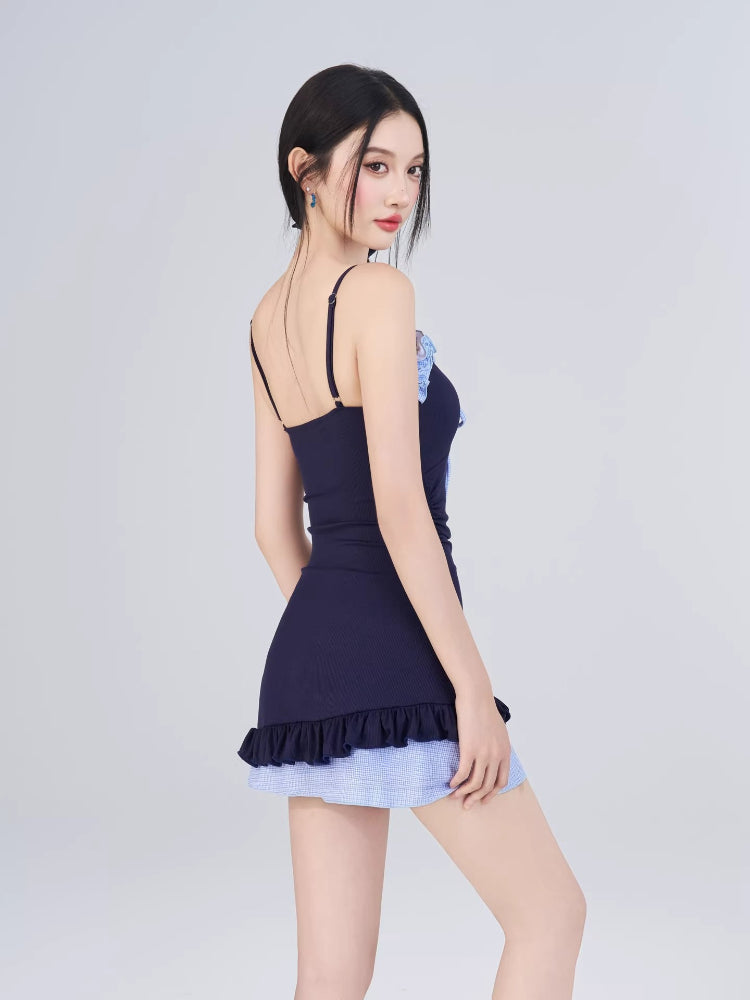 Back view of the model wearing the navy blue one-piece swimsuit with light blue gingham hem.