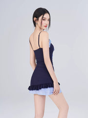 Back view of the model wearing the navy blue one-piece swimsuit with light blue gingham hem.