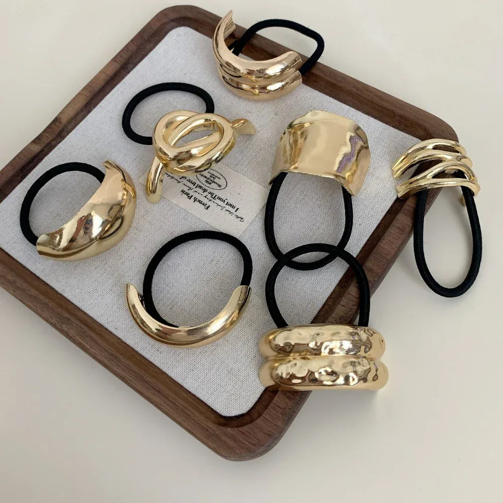 Assortment of gold-tone abstract shape hair ties arranged in a tray