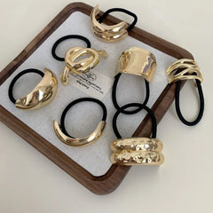 Assortment of gold-tone abstract shape hair ties arranged in a tray