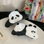 Two panda hair claw clips on a white surface with a textured bag in the background