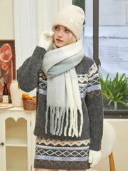 Woman in a cream beanie, multi-colored fringed scarf, and gray knit sweater dress with Fair Isle pattern.