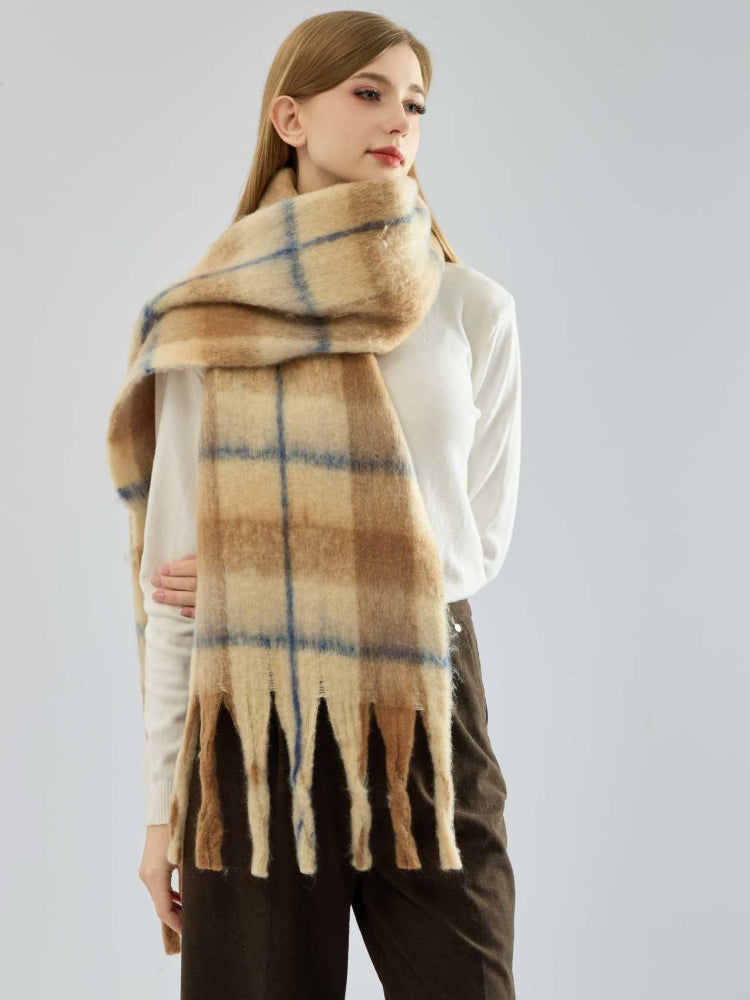 Close-up of a tan and blue plaid fuzzy knit scarf with fringe.