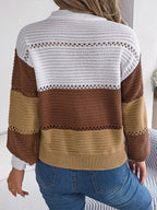 Back view of a woman wearing a brown, tan, and white color block knit sweater with a v-neck and button details, paired with blue jeans.