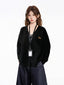 Model wearing a black V-neck knit cardigan with an embroidered dachshund detail, a black tank top, and dark wash wide-leg jeans, with an ID badge holder around her neck.