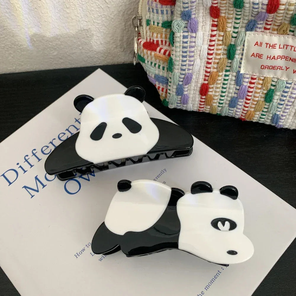 Two panda hair claw clips on a book with a textured bag in the background