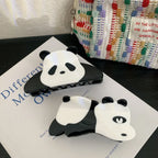 Two panda hair claw clips on a book with a textured bag in the background