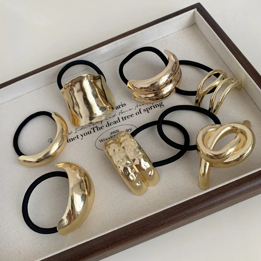 Close-up of gold-tone abstract shape hair ties in a tray