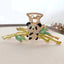 Close-up of a gold claw clip featuring a panda charm adorned with rhinestones, nestled on a bamboo branch with green enamel leaves.