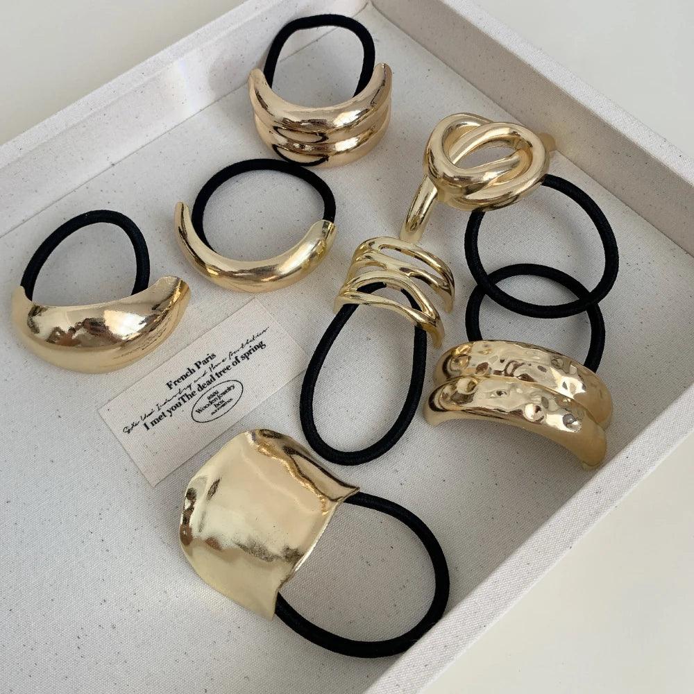 Collection of gold-tone abstract shape hair ties in a tray