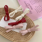 collection of colorful resin bow barrettes including red, white, and pink, arranged on a woven basket