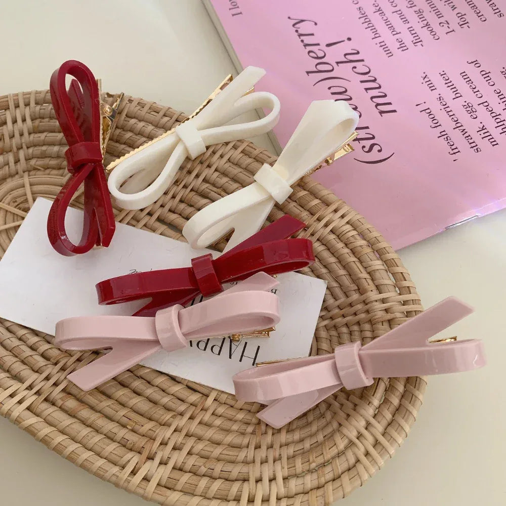 collection of colorful resin bow barrettes including red, white, and pink, arranged on a woven basket