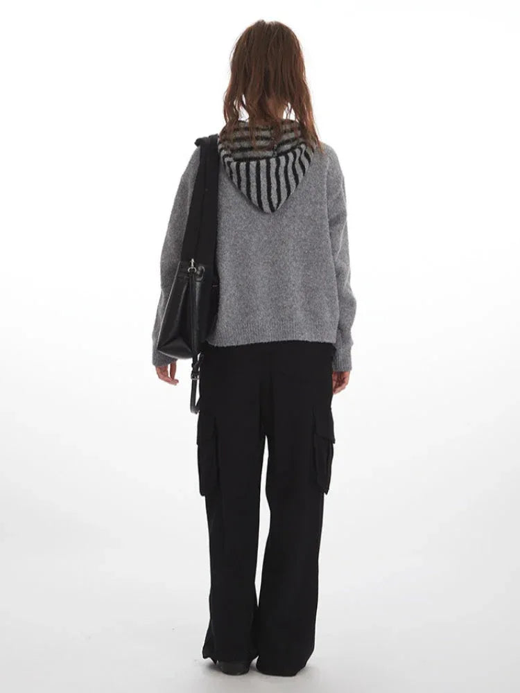 Woman wearing a grey knit sweater with a striped scarf and black cargo pants, back view.