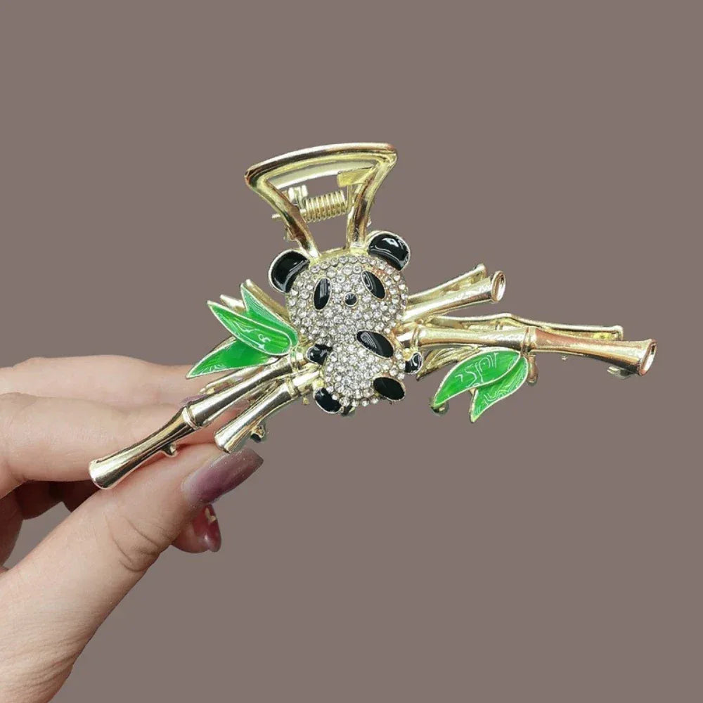 A gold claw clip with a panda and bamboo motif, presented from a slightly angled perspective.
