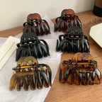 collection of six hair claw clips in black and tortoise shell patterns arranged on a wooden surface