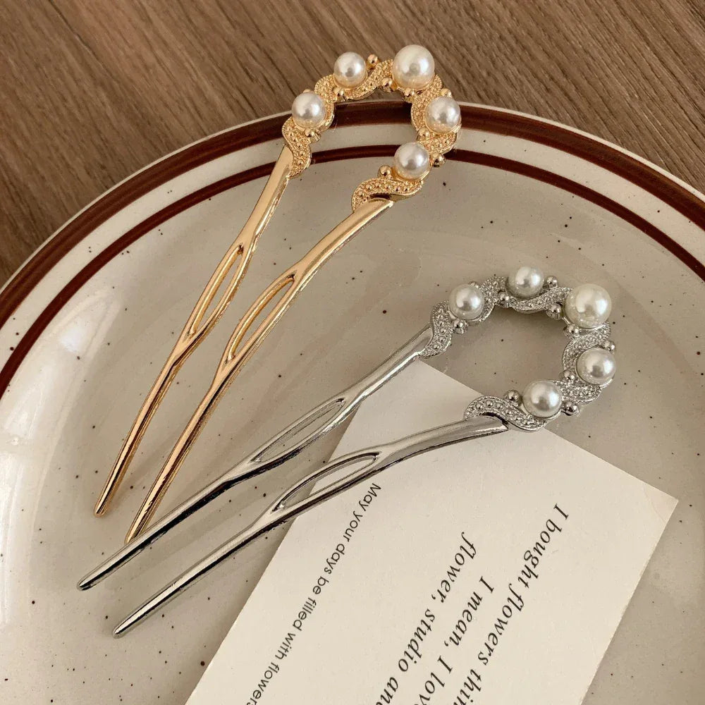 Gold and silver U-shaped hairpins with pearl and rhinestone accents on a plate