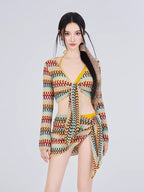 Woman wearing a crocheted knit long-sleeve tie-front crop top, wrap skirt, and bikini bottom