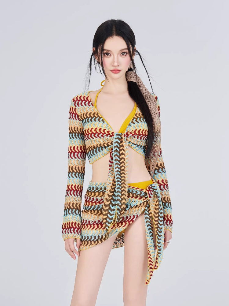 Woman wearing a crocheted knit long-sleeve tie-front crop top, wrap skirt, and bikini bottom