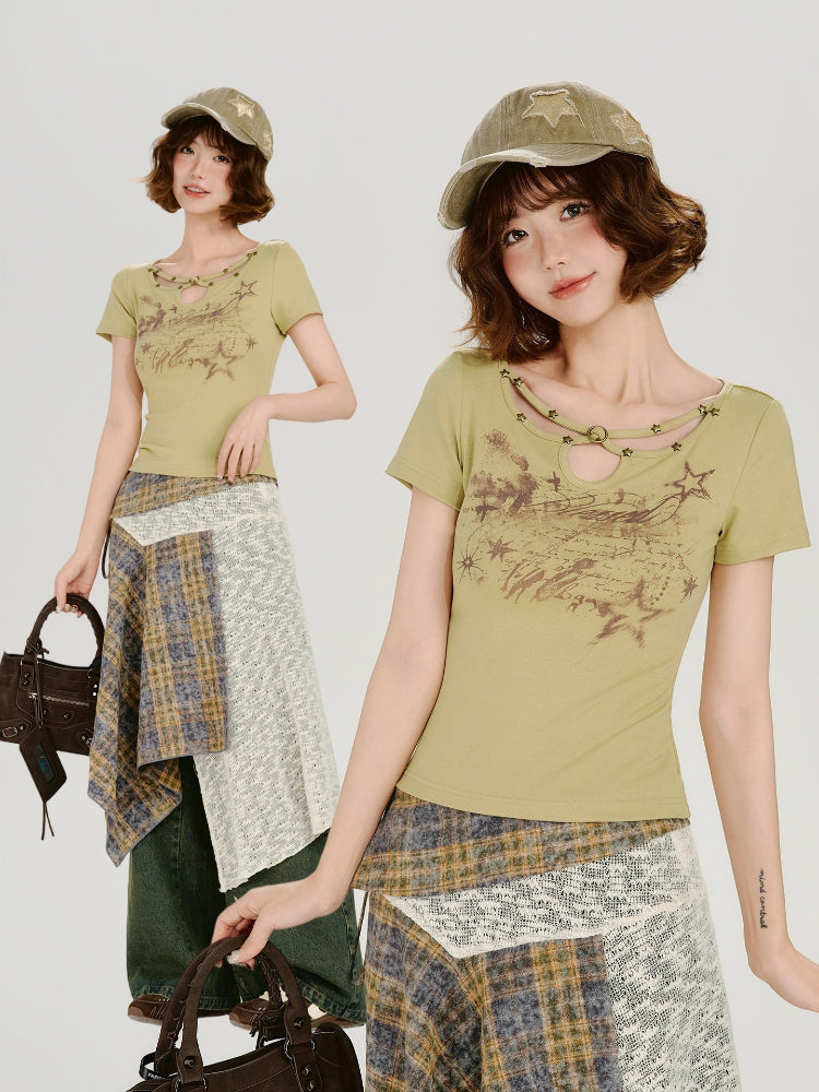 Full-body shot of a model wearing a light green short-sleeve t-shirt with a cutout neckline and star details, paired with an asymmetrical plaid skirt and a khaki baseball cap, holding a brown handbag. A smaller inset image shows a close-up of the outfit.