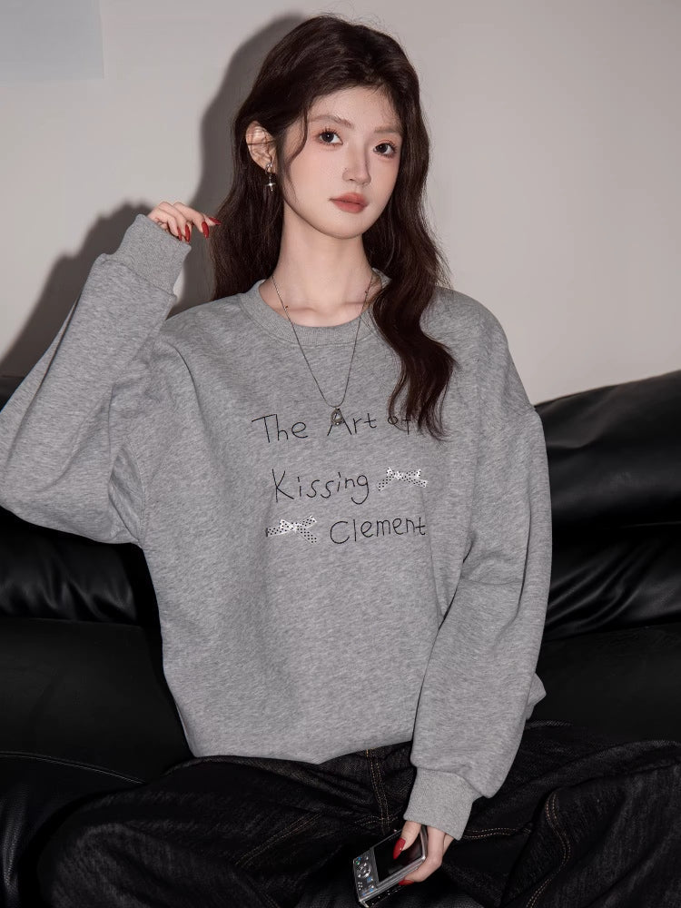 Woman wearing a grey crew neck sweatshirt with graphic print