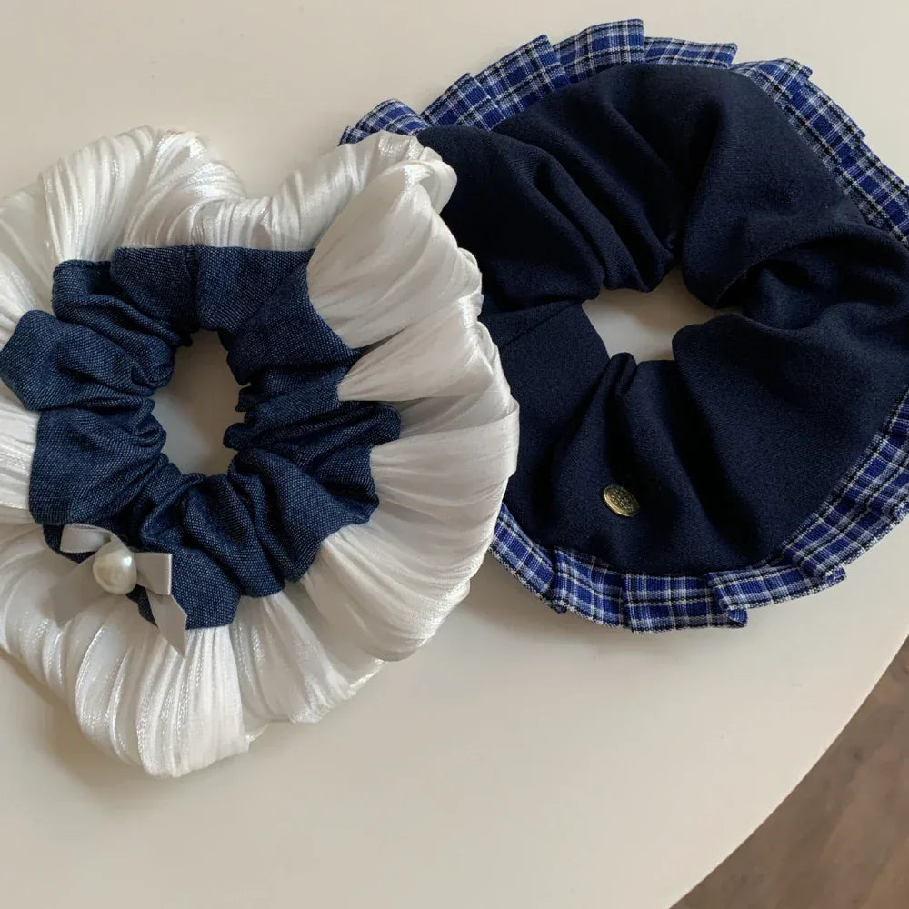 Two scrunchies, one white and denim with pearl, the other navy with plaid trim