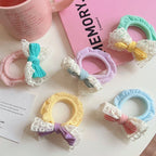 Close-up of pastel scrunchies with bows and lace trim on a pink book