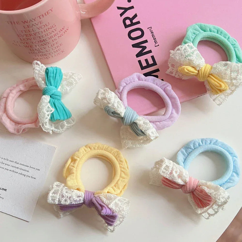 Close-up of pastel scrunchies with bows and lace trim on a pink book