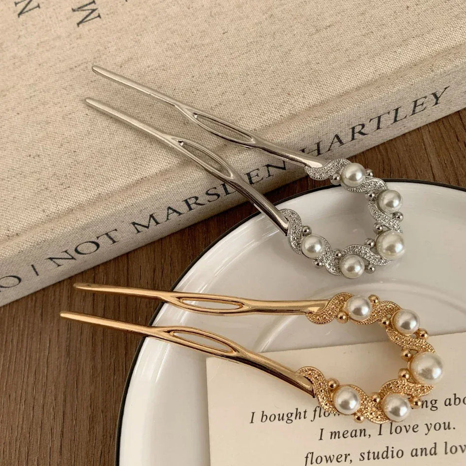 Two hairpins, one gold and one silver, with pearl and rhinestone details resting on a book Secondary image