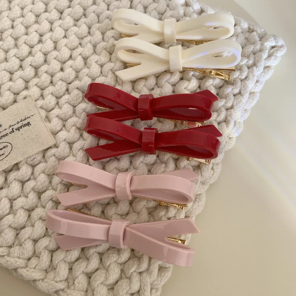 stack of resin bow barrettes in pink, red, and white arranged on a textured textile