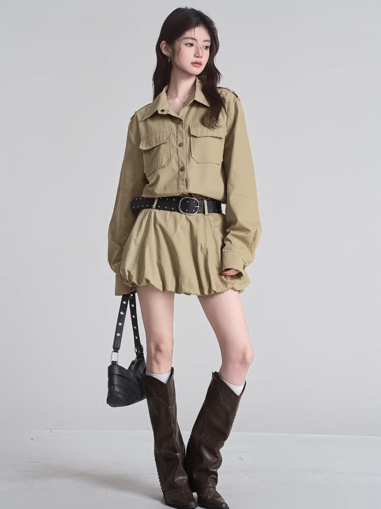 Full body shot of a woman wearing a tan button-down shirt dress, black studded belt, white socks, and brown boots.
