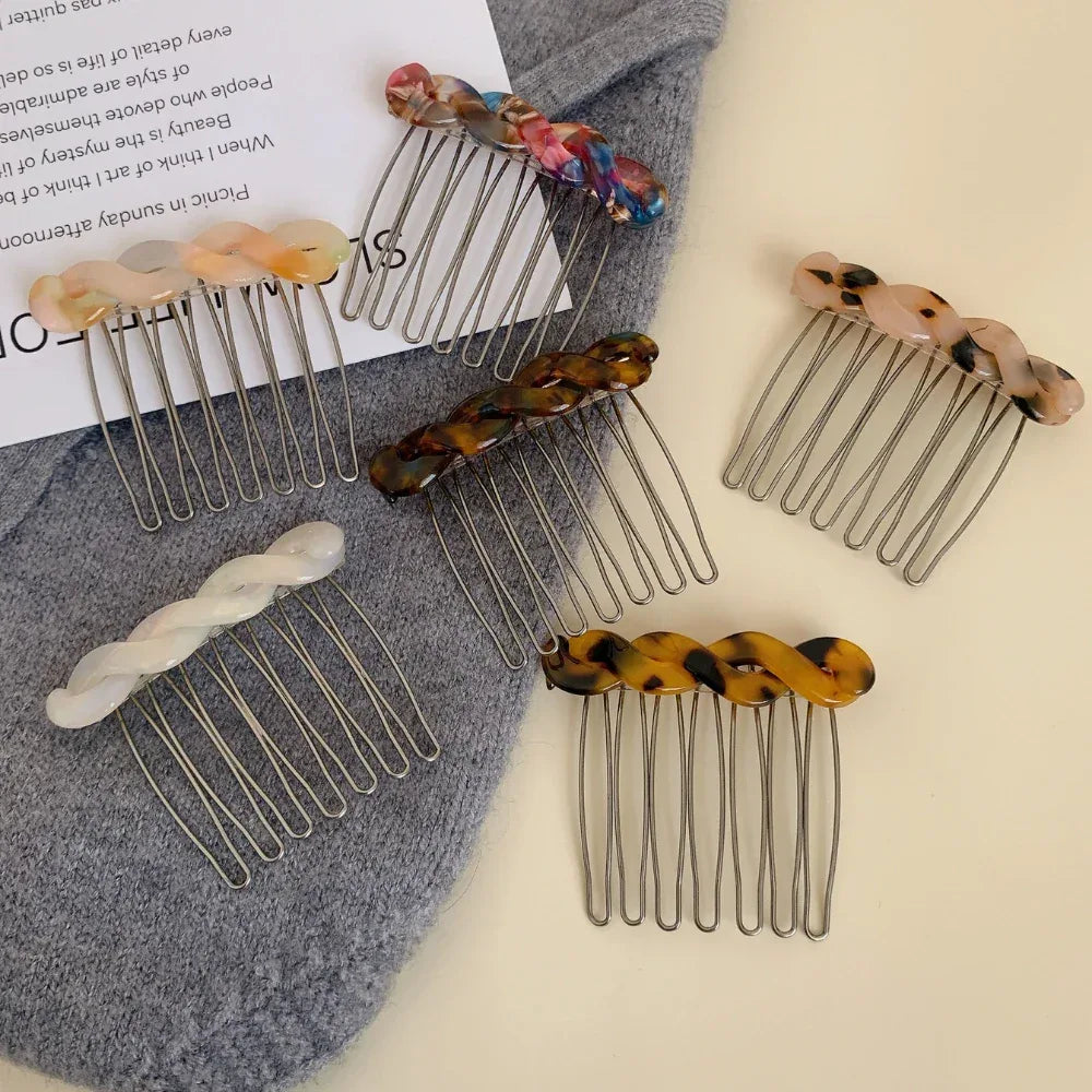 Assortment of marbled resin twisted hair combs with metal teeth scattered on a grey garment