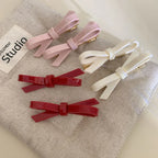various colored resin bow barrettes (pink, white, red) laid out on a neutral fabric