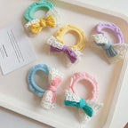 Various pastel scrunchies with bows and lace trim arranged on a white tray