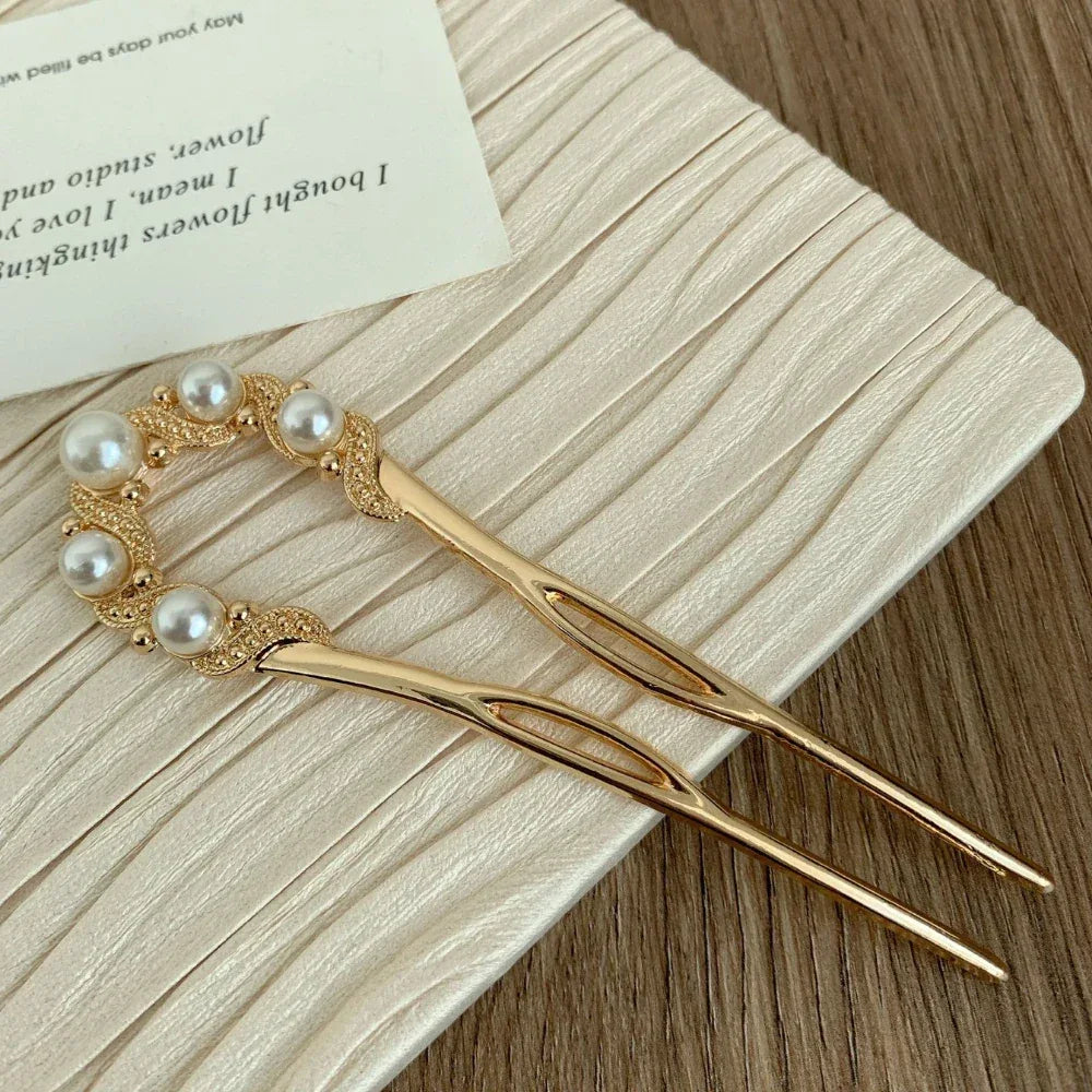 Close-up of a gold U-shaped hairpin with pearl and rhinestone details