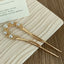 Close-up of a gold U-shaped hairpin with pearl and rhinestone details