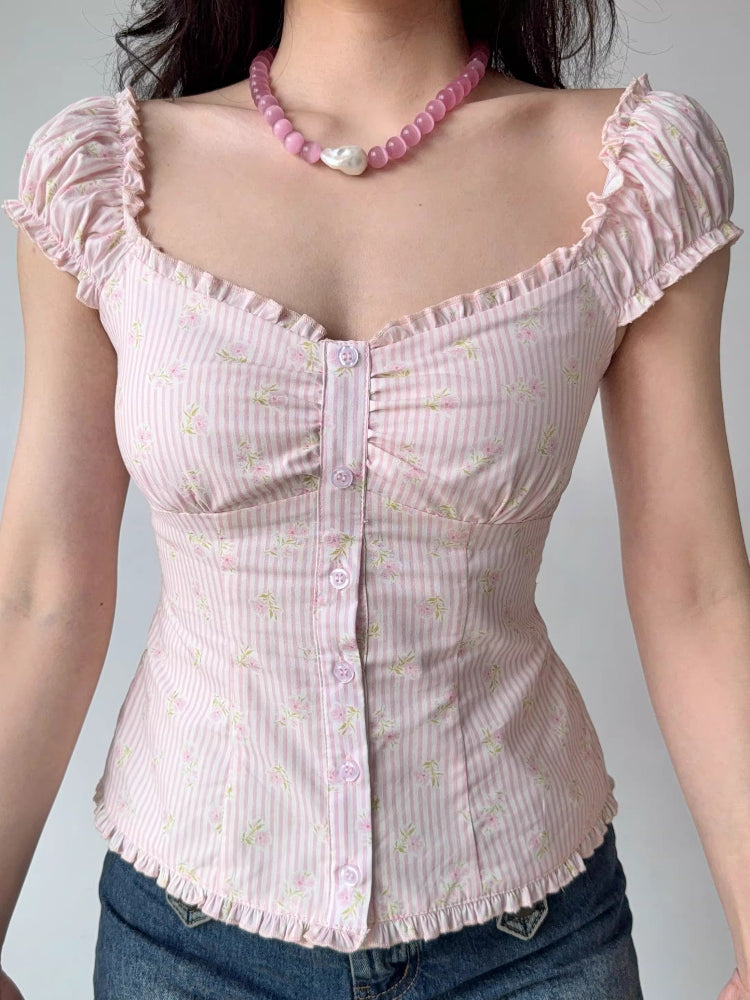 Front view of a woman wearing a pink striped and floral print top with ruffle trim and puff sleeves.