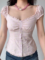 Front view of a woman wearing a pink striped and floral print top with ruffle trim and puff sleeves.