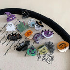 Collection of Halloween-themed hair clips including a witch hat, ghost, bat, pumpkin, skull, cat, spiderweb, and monster