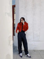 Woman wearing a red fur jacket and black pants talking on the phone