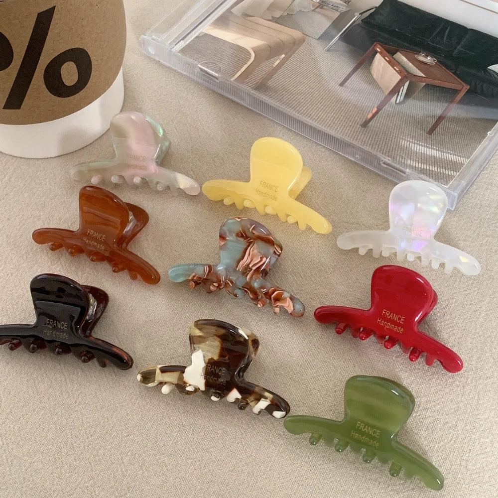Group of acetate claw hair clips in different colors and patterns, some with "FRANCE Handmade" inscription