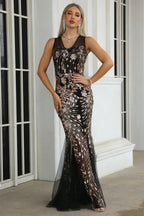 Woman wearing a black sleeveless mermaid gown with gold sequin embellishments and a sheer tulle hem.
