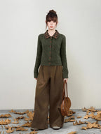 Woman holding a brown handbag and wearing a green cable knit cardigan