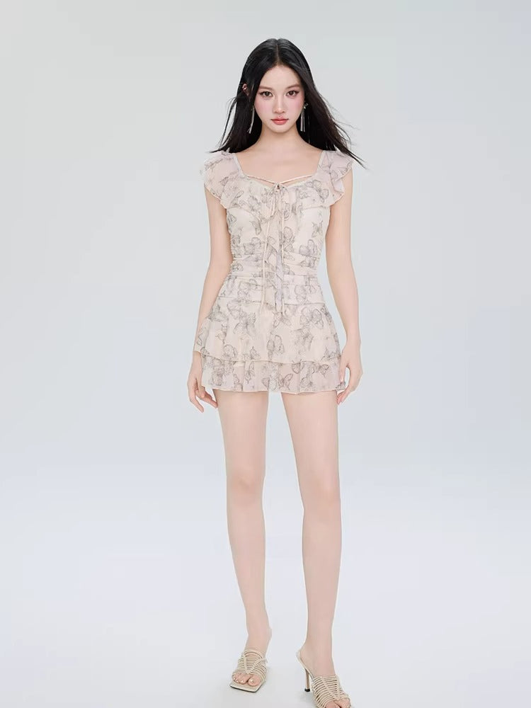 Full-length view of a model in a butterfly print dress with ruffled sleeves and a tiered skirt.