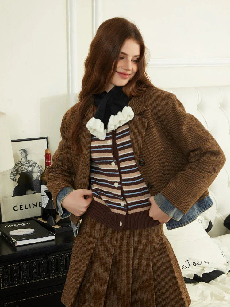 Woman wearing a brown plaid blazer, striped knit top, and brown pleated skirt.