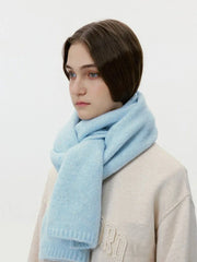 Model wearing a cream sweatshirt and a thick light blue knit scarf wrapped around her neck, side view.