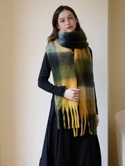 Close-up of a woman wearing a cozy, oversized plaid scarf in shades of green and yellow.