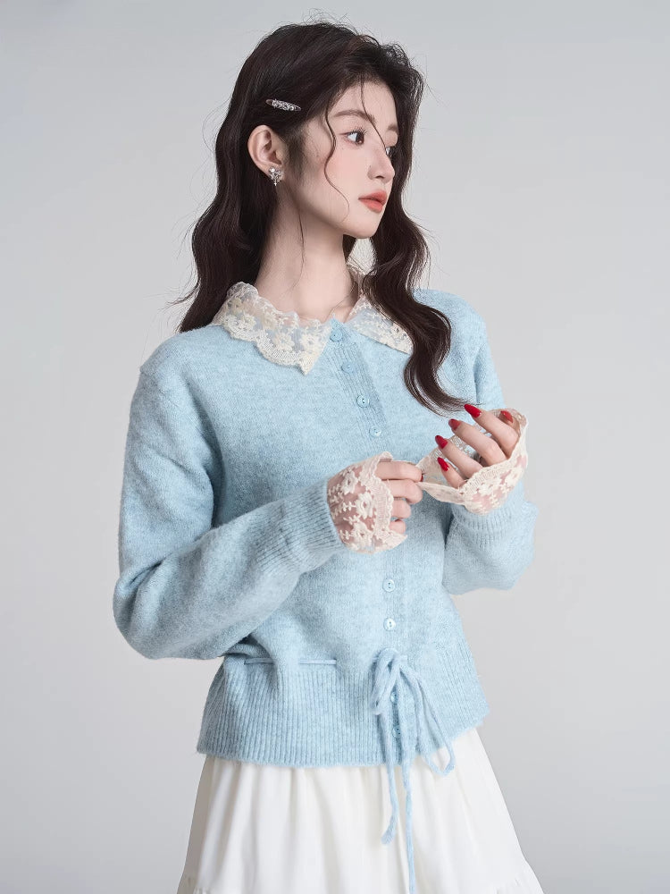 Woman adjusting the lace cuffs of a light blue knit cardigan.
